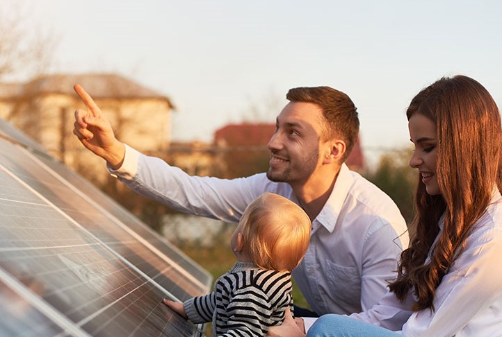 Ein Vater zeigt seiner Familie ein Photovoltaik Modul von Klarsolar für ihre Solaranalge finanziert durch die SWK Bank.